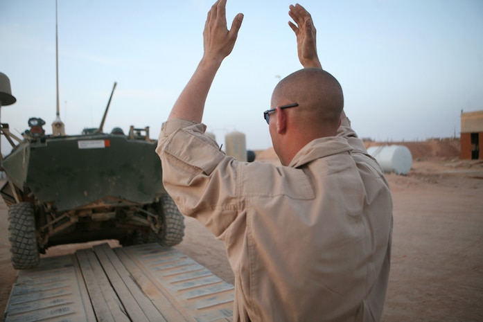 Cpl. Nathan E. Burrell, a logistics vehicle system operator with Motor Transport Platoon, 2nd Light Armored Reconnaissance Battalion, Regimental Combat Team 5, ground-guides a damaged light armored vehicle onto a cargo trailer during a vehicle recovery mission in western Anbar province, Iraq, April 25. Burrell, 21, from Bloomingdale, Ill., is part of a wrecker team that provides recovery service to units in and around Anbar province to continue operations.