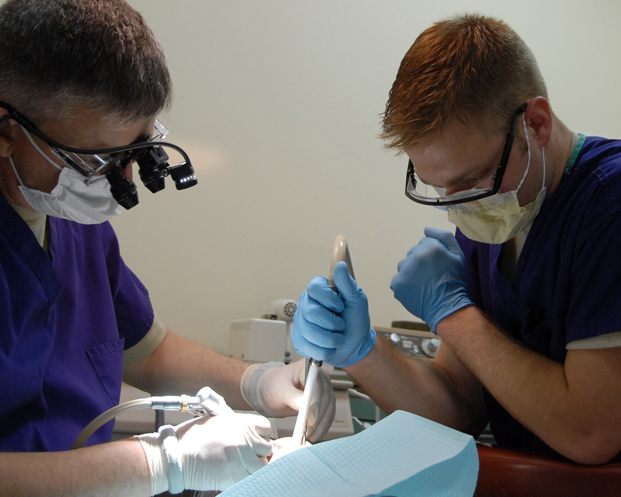 SOUTHWEST ASIA -- Staff Sgt. Lucas Angil, a dental assistant with the 386th Expeditionary Medical Group, assists dentist Lt. Col. Robert VanDevelde with a patient April 7, 2008, at a clinic in the Persian Gulf Region. (U.S. Air Force photo/Tech. Sgt. Michael O'Connor)