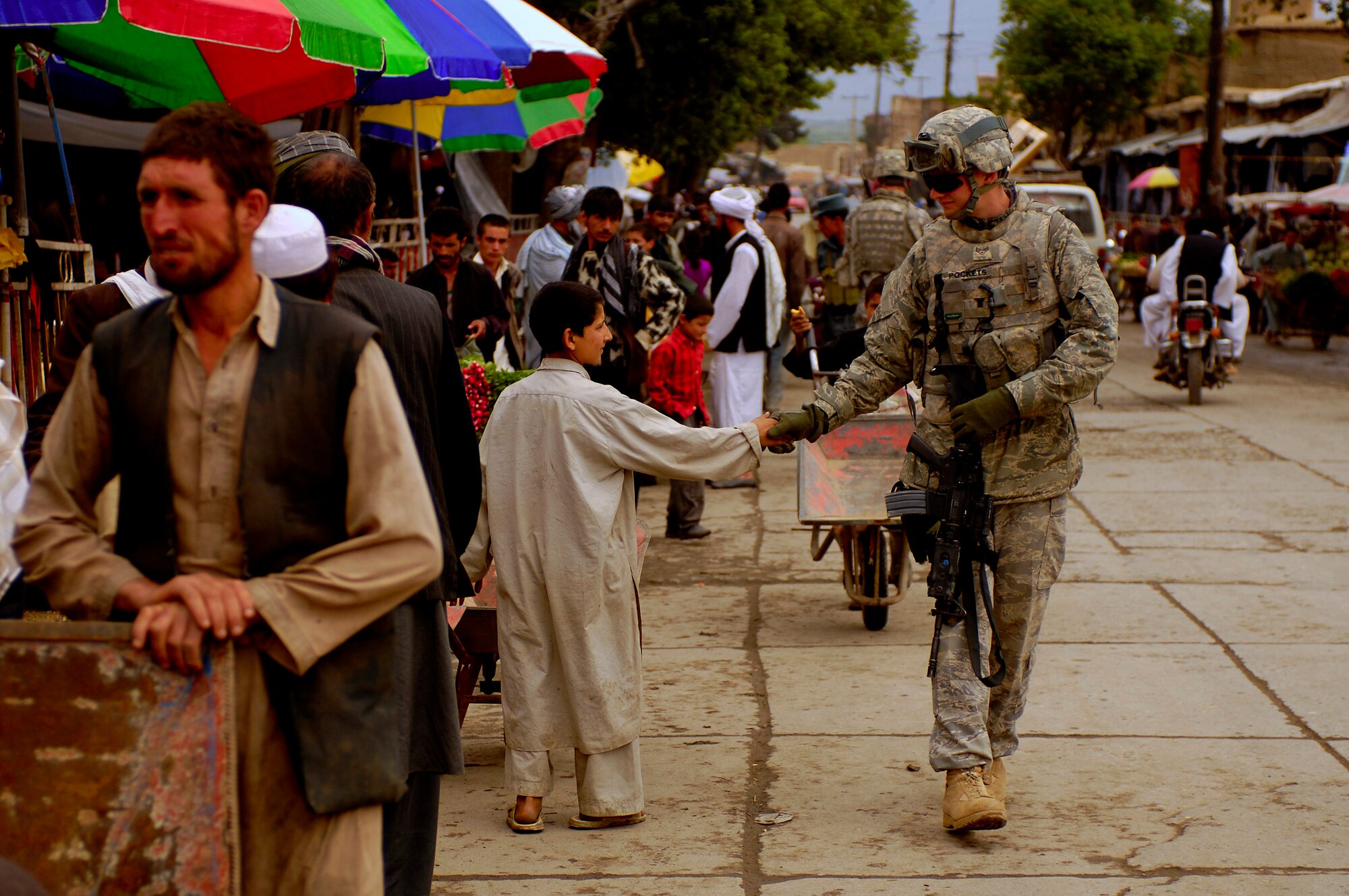 PARWAN PROVINCE, Afghanistan - Senior Airman Mark Ostrander shakes hands with a young boy during a foot patrol here April 22.  Airman Ostrander, Police Technical Advisory Team member, Bagram Provincial Reconstruction Team, is deployed from the 55th Security Forces Squadron, Offutt Air Force Base, Neb. (U.S. Air Force photo by Master Sgt. Andy Dunaway)