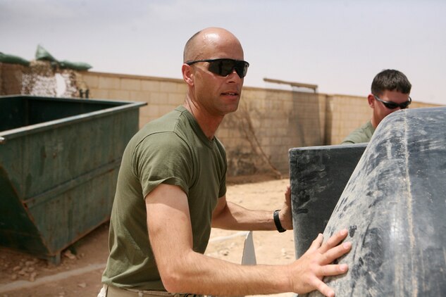 Chief Petty Officer Truman A. Gartman, chief petty officer of the Battalion Aid Station, 2nd Light Armored Reconnaissance Battalion, Regimental Combat Team 5, assists his sailors rolling a giant water tank in preparation of building a 7-foot swimming pool at Camp Korean Village, Iraq, April 30. Gartman, 38, from San Angelo, Texas, has been working with Marines for more than 14 years of his 20 years with the Navy.