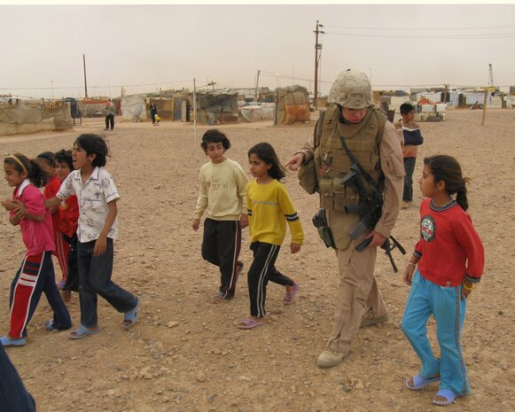 Lance Cpl. Jennifer Shell, a military policewoman who is currently serving as the chow hall manager at a combat outpost near the Port of Trebil on the Iraq-Syrian border, enjoys a visit with children at an Iranian Kurd refugee camp in the region on May 15.  Shell is with Military Police Company B, 4th Marine Logistics Group, based in North Versailles, Pa.  The Marines at the combat outpost routinely bring food and other items to the campâ??s residents to augment the supplies they receive from the United Nations.  Shell formed close bonds with some of the campâ??s residents and even helped cook dinner on one of her visits.
