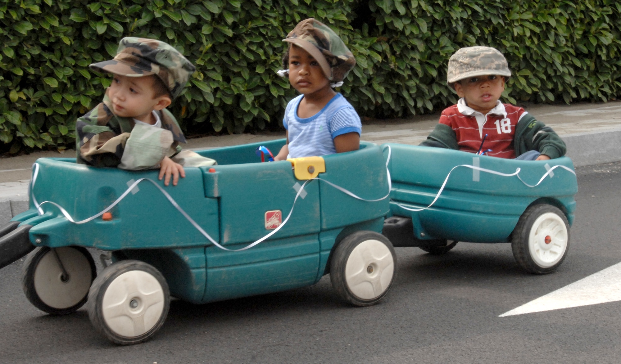 AVIANO AIR BASE, Italy--Nathan Weintraub, Miya Clair and Quentin Whitted wheel around in a wagon caravan during the annual month of the military child parade at Area 1. (U.S. Air Force photo/Airman 1st Class Tabitha Mans).