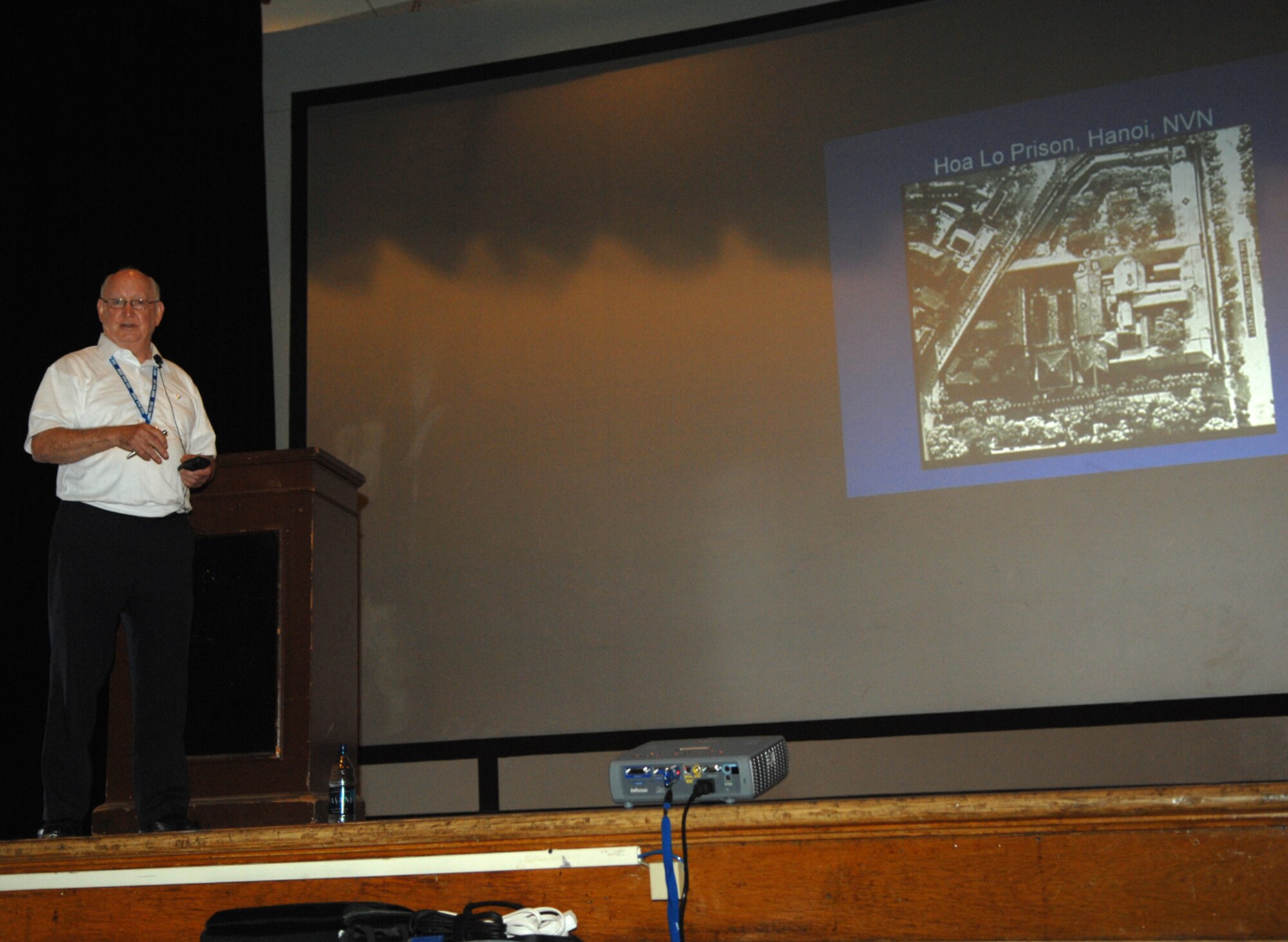 Retired Air Force Colonel Elmo "Mo" Baker, once a member of the 355th, shows the audience a map of Hoa Lo Prison or the Hanoi Hilton as it is known as. Colonel Baker was a Prisoner of War at the prison from 1967 to 1973. (U.S. Air Force photo by Senior Airman Alesia Goosic)