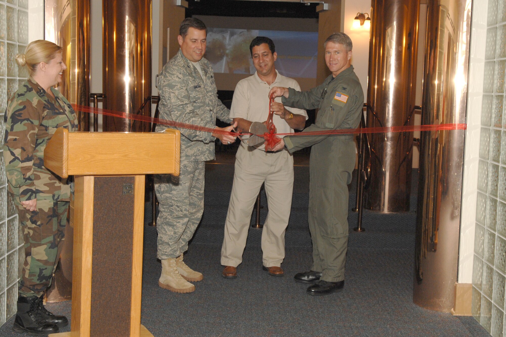 (Left to right) Capt. Charri Leonard, Airman & Family Readiness Center flight commander, looks on as Col. Mike Smietana, 1st Special Operations Mission Support Group commander, Mark Monno, A&FRC, and Col. Mark Alsid, 1st Special Operations Wing vice commander, cut the ribbon for the Commando Auditorium April 28. The auditorium, which used to be the base theater, underwent a $200,000 renovation and is now available for functions ranging from graduations to video teleconferences. (U.S. Air Force photo/Airman 1st Class Kimberly Darnall)