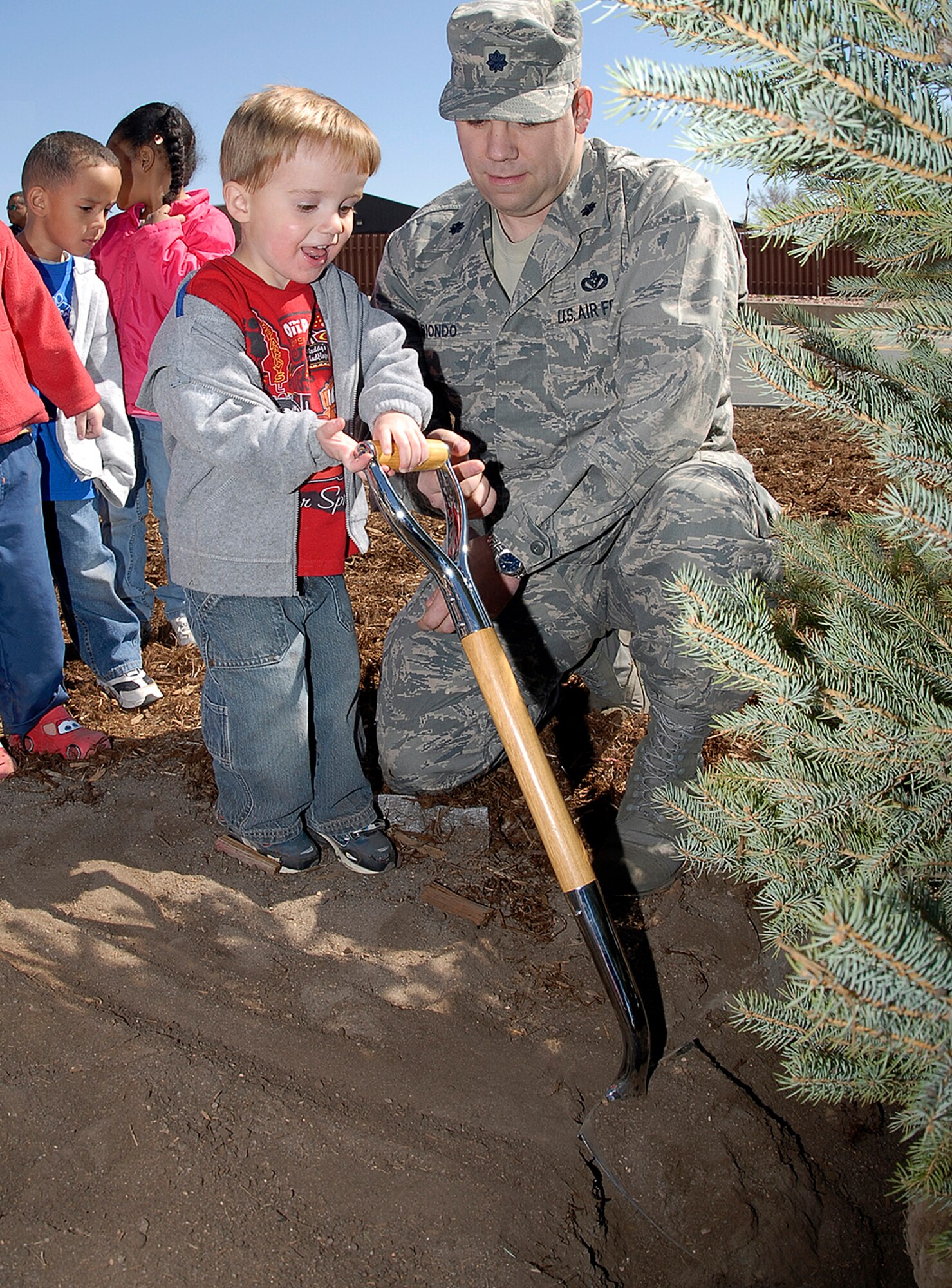 Lt. Col. Craig Biondo, 21st Mission Support Group deputy commander, helps a boy plant a blue spruce outside the bioenvironmental engineering building in honor of Arbor Day April 22 at Peterson Air Force Base, Colo. Peterson is one of more than 3,000 “Tree Cities” in the U.S., an honor given to cities with tree planting and management programs. This is the base's 14th consecutive Tree City USA award and seventh consecutive Growth Award for increasing the number and density of trees on base. (U.S. Air Force photo/Rob Bussard) 