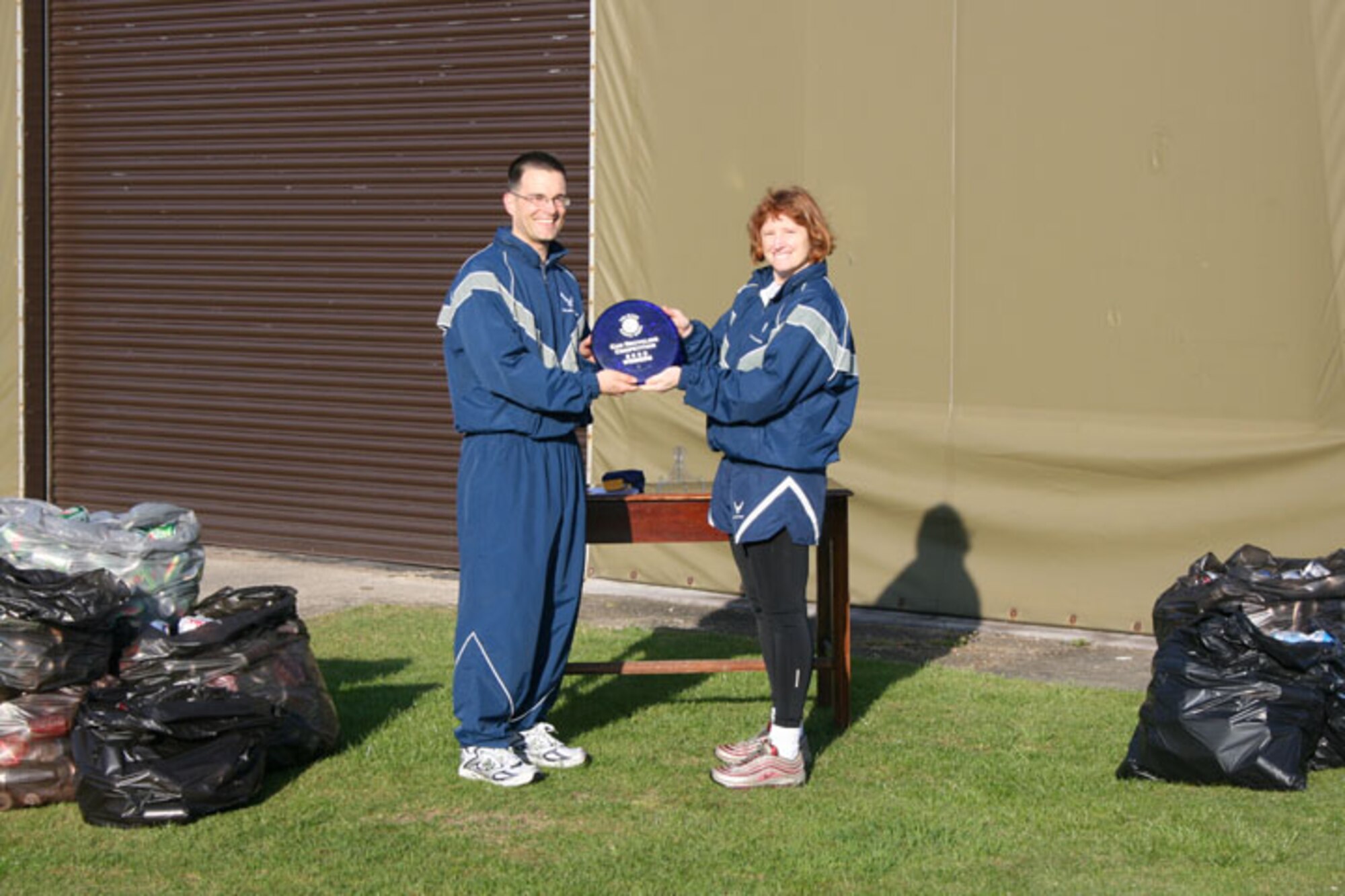 Col. Kimberly Toney, 501st Comabt Support Wing commander, presents Lt. Col. Keith Welch, 423rd Civil Engineer Squadron commander, with a trophy in recognition of the squadron winning the aluminum can recycling competition.