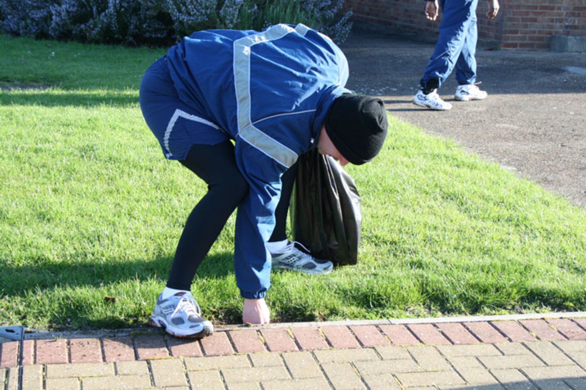Master Sgt. Jerry Dire, 423rd Air Base Squadron, tries to get a glass bottle out of the ground outside the education center at RAF Alconbury. Base members fanned out across the base to pick up trash and other debris as part of the Tri-Base Earth Day event.
