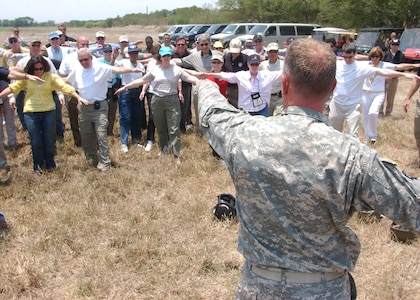 Army Staff Sgt. David Hattan, an Army Forces parachute rigger, instructs Joint Civilian Orientation Conference participants on how to direct a helicopter during the disaster response slingload demonstration. JCOC visited Soto Cano Air Base, Honduras April 24 to take a glimpse into the Joint Task Force-Bravo mission. (Photo by Martin Chahin)                  