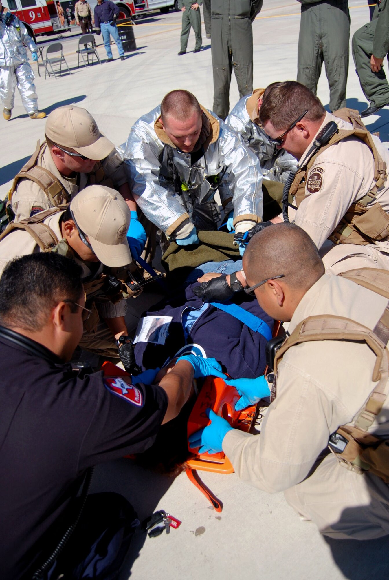 LAUGHLIN AIR FORCE BASE, Texas – Laughlin firefighters work along side Del Rio paramedics and Border Patrol to assist an air show attendee with her simulated injuries after a mock grease fire on the flight line April 18. Laughlin conducted multiple exercises to prepare for the upcoming air show May 10. (U.S. Air Force photo by Airman 1st Class Sara Csurilla)