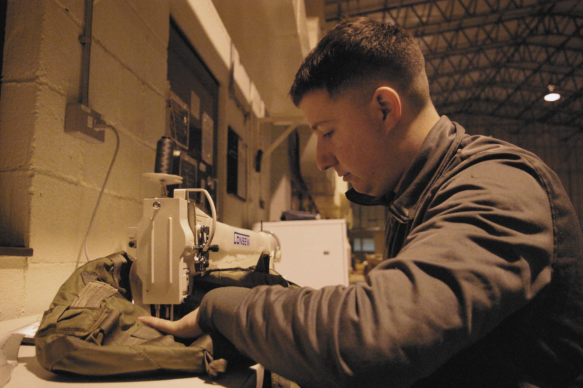 Staff Sgt. Sean Basile, 352nd Operation Support Squadron, uses a long-arm-medium-size sewing machine to adapt a G-14 deployment bag for a 22-foot cargo parachute. These bags are the only type to receive this type of modification in the Department of Defense; they have to be tailored to a certain standard for low-level air drops by special operations forces C-130 aircraft. The six-year Tulsa Oklahoma native has been working long hours over the past couple weeks keeping cargo and personnel chutes packed and ready for special operators to meet their individual training schedules, whether that means they’re in the cockpit, the cargo bay or leaping out the back of the airplane. (U.S. Air Force photo by Master Sgt. Dennis Brewer)
