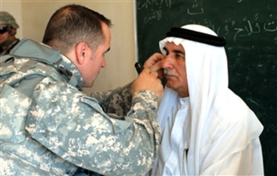 U.S. Army Capt. Joe Dominguez, Task Force XII physician’s assistant, peers into the eyes of an Iraqi man who came to a cooperative medical clinic in his village on April 21, 2008.  The clinics allow Multinational Division Baghdad’s medics the chance to help Iraqis in remote villages.
