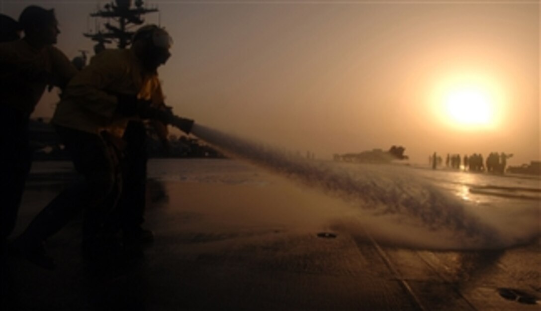 Sailors use a fire hose to spray down the flight deck of the aircraft carrier USS Harry S. Truman (CVN 75) in an effort to remove built up dirt and grime during a sunset scrubbing exercise as the ship operates in the Persian Gulf on April 15, 2008.  Truman is on deployment supporting maritime security operations.  