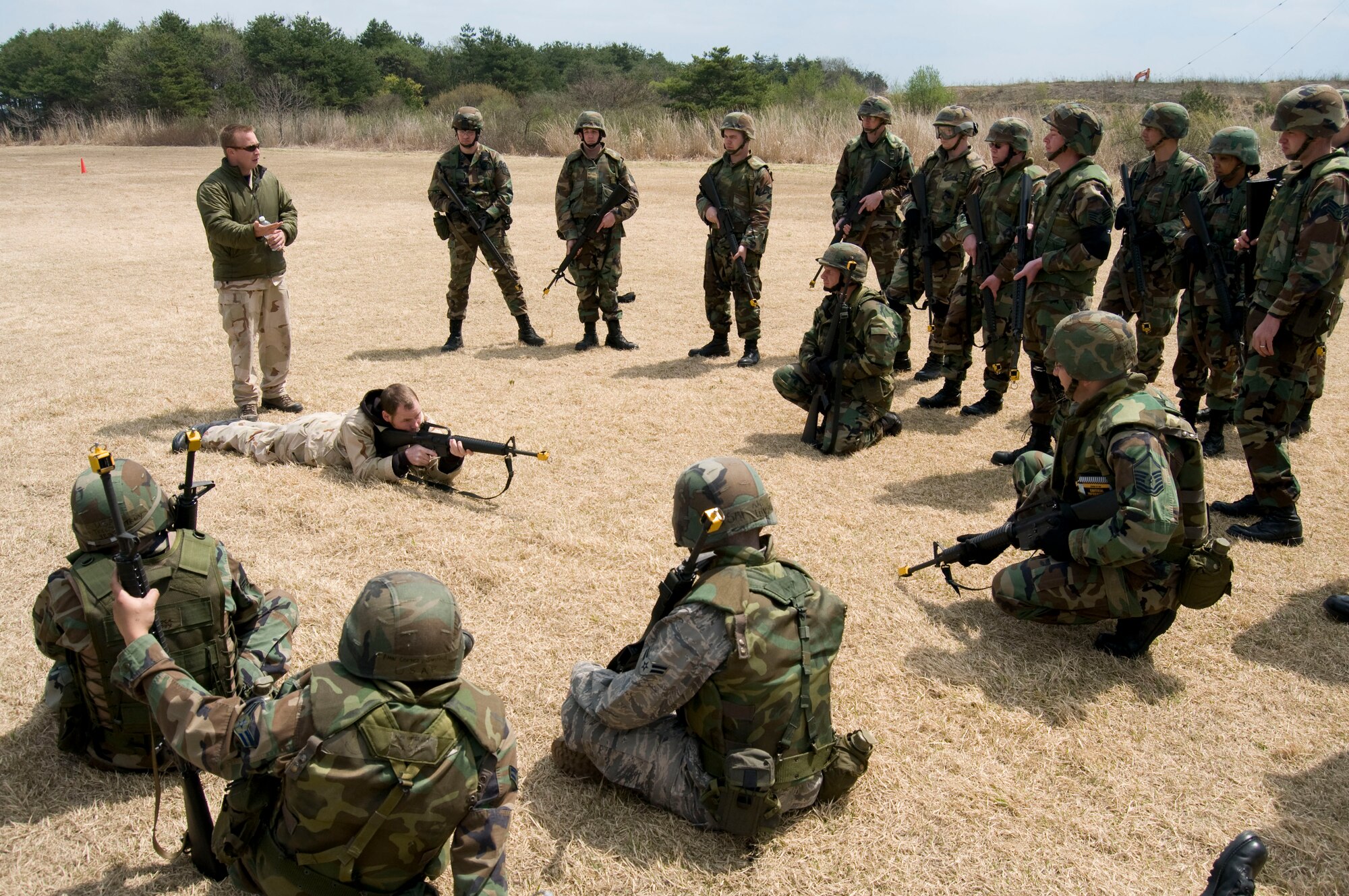 MISAWA AIR BASE, Japan -- Jack Anderson, analyst for ANSER Analytic Services Inc., demonstrates proper prone position firing while Donnie Hayes, another analyst for ANSER, gives instructions to the surrounding Airmen at Camp Defender on April 25, 2008. Mr. Anderson and Mr. Hayes instructed Airmen attending Expeditionary Combat Skills Training on indvidual movement techniques to include low crawl, high crawl, and rushing. (U.S. Air Force photo by Senior Airman Samuel Morse)