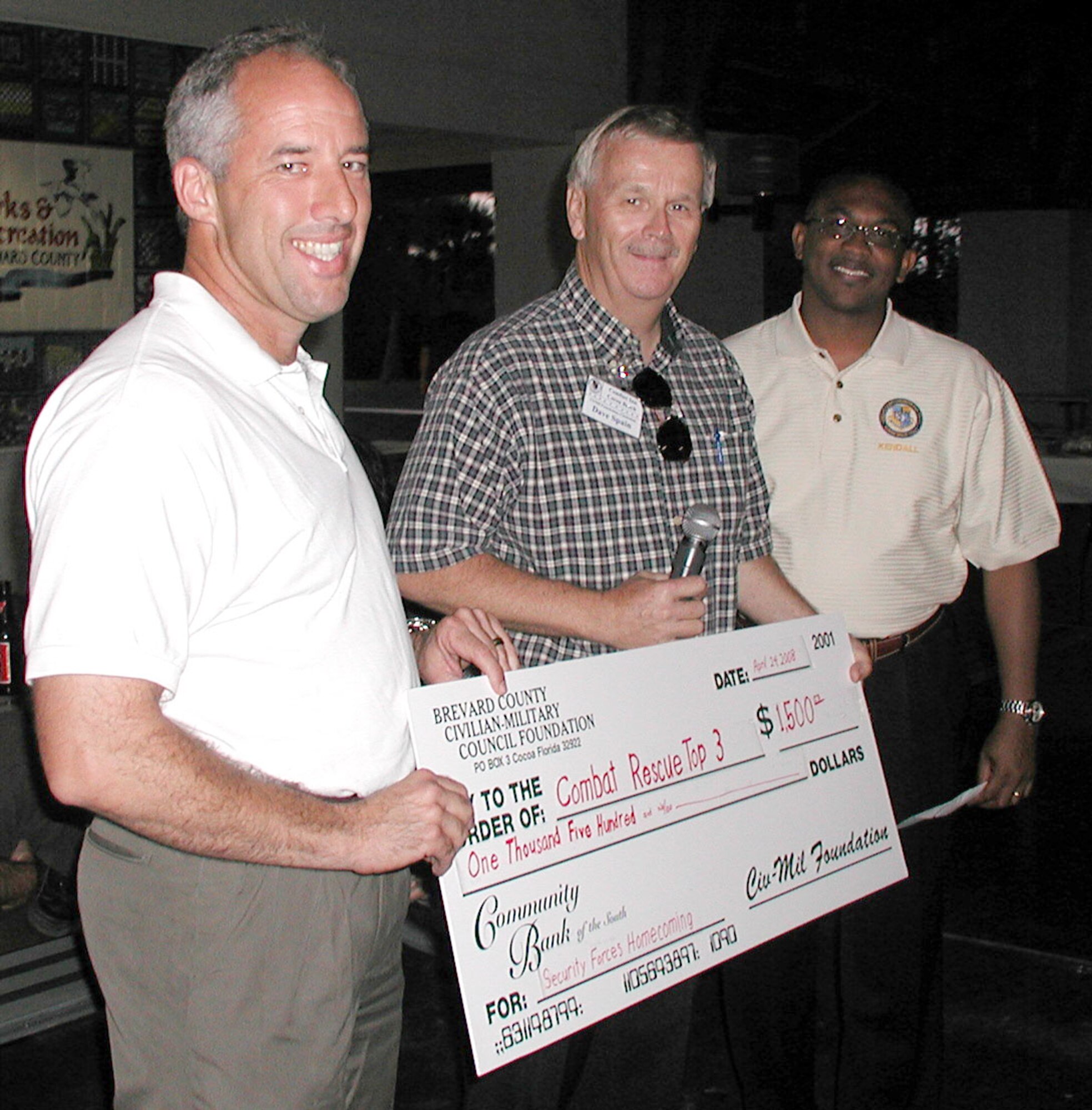 Brevard County Florida Civilian-Military (CivMil) Council boardmembers, Mr. David Spain and Mr. Kendall Moore (middle and right), presented a check for $1,500 to 920th Rescue Wing Commander, Col. Steve Kirkpatrick (left), April 24 for Rescue Wing Reservists who were deployed in support of Operation Iraqi Freedom. Twelve of the Air Force Reservists arrived home safely after completing a six-month deployment to Kirkuk Air Base, Iraq.  The reservists originally deployed with 13 Airmen, but one team member, Senior Airman Diane Lopes, was severely wounded during a September mortar attack and evacuated to Walter Reed Army Medical Center, Md. where she continues to undergo physical therapy for her injuries.  Airman Lopes sent a video message to her fellow Airmen here to watch while they enjoy a welcome-home celebration at a restaurant local to Patrick Air Force base with their families.  
