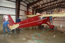 MINOT AIR FORCE BASE, N.D.— 1st Lt. Matthew Stigler and 2nd Lt. Grant Smith from the 23rd Bomb Squadron, help Senior Airman Alan Adair, 5th Logistics Readiness Squadron, clean a 1935 Fairchild F-24 airplane. Airmen from the base volunteered their time and effort to help clean the Dakota Territory Air Museum after recent renovations. (U.S. Air Force photo by Senior Airman Cassandra Jones)