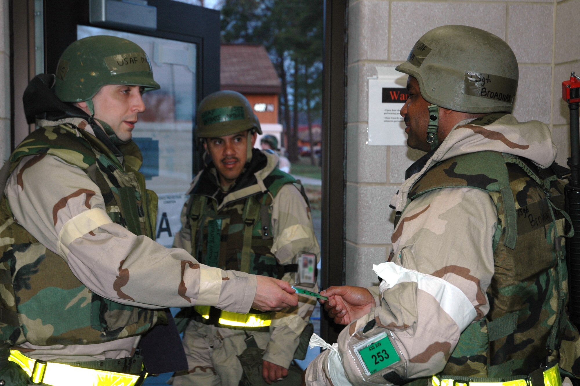 Maj. Kenneth Gornic (left), hands over his exercise identification badge to Tech. Sgt. William Broadnax, 436th Civil Engineer Squadron. Sergeant Broadnax served as a door guard, responsible for the accountability and security of the building's occupants and assets. Tech. Sgt. Antonio Infante, 436th Legal Office is also pictured. Team Dover deployed to Alpena, Mich., April 20 to 25 to train for the upcoming Operational Readiness Inspection in July. 