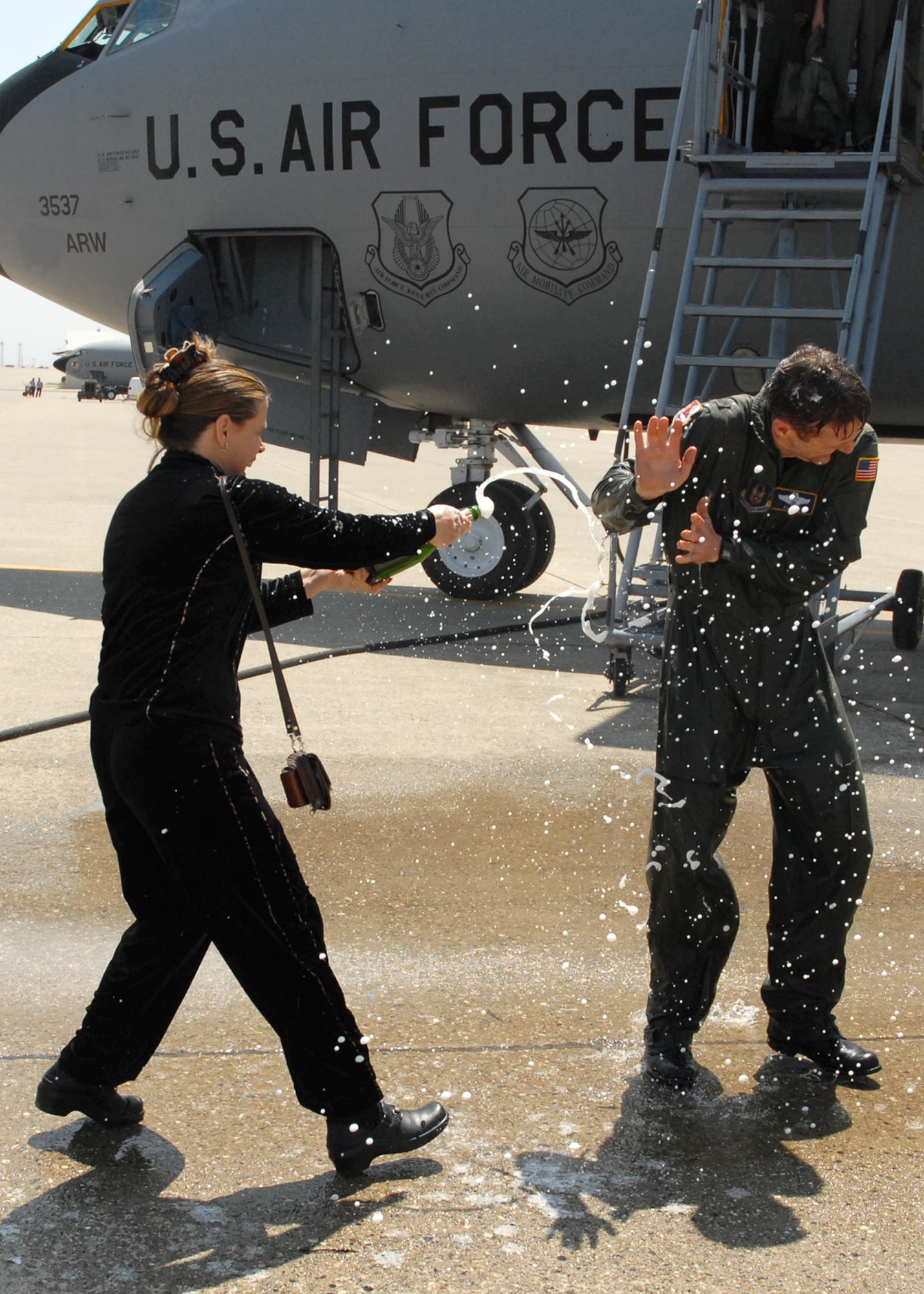 BEALE AIR FORCE BASE, CALIF. -- Lisa Reif, wife of 940th Air Refueling Wing commander Col. Al Reif, follows up his traditional "fini" flight water dousing with a cold champagne shower Apr. 25, 2008. An Air Force Reservist, Col. Reif flew one of the last two KC-135R Stratotankers still assigned to the wing. Those jets depart May 3, 2008, for the 916th ARW, Seymour Johnson AFB, N.C. While the 940th ARW is drawing down its legacy KC-135R mission, as directed by the Base Closure and Realignment Commission, Beale Reservists are partnering with active duty Airmen to fly the RQ-4 Global Hawk, an unmanned surveillance and reconnaissance jet, as well as support emerging command and control, and intelligence missions. (U.S. Air Force photo/Master Sgt. Ellen L. Hatfield)