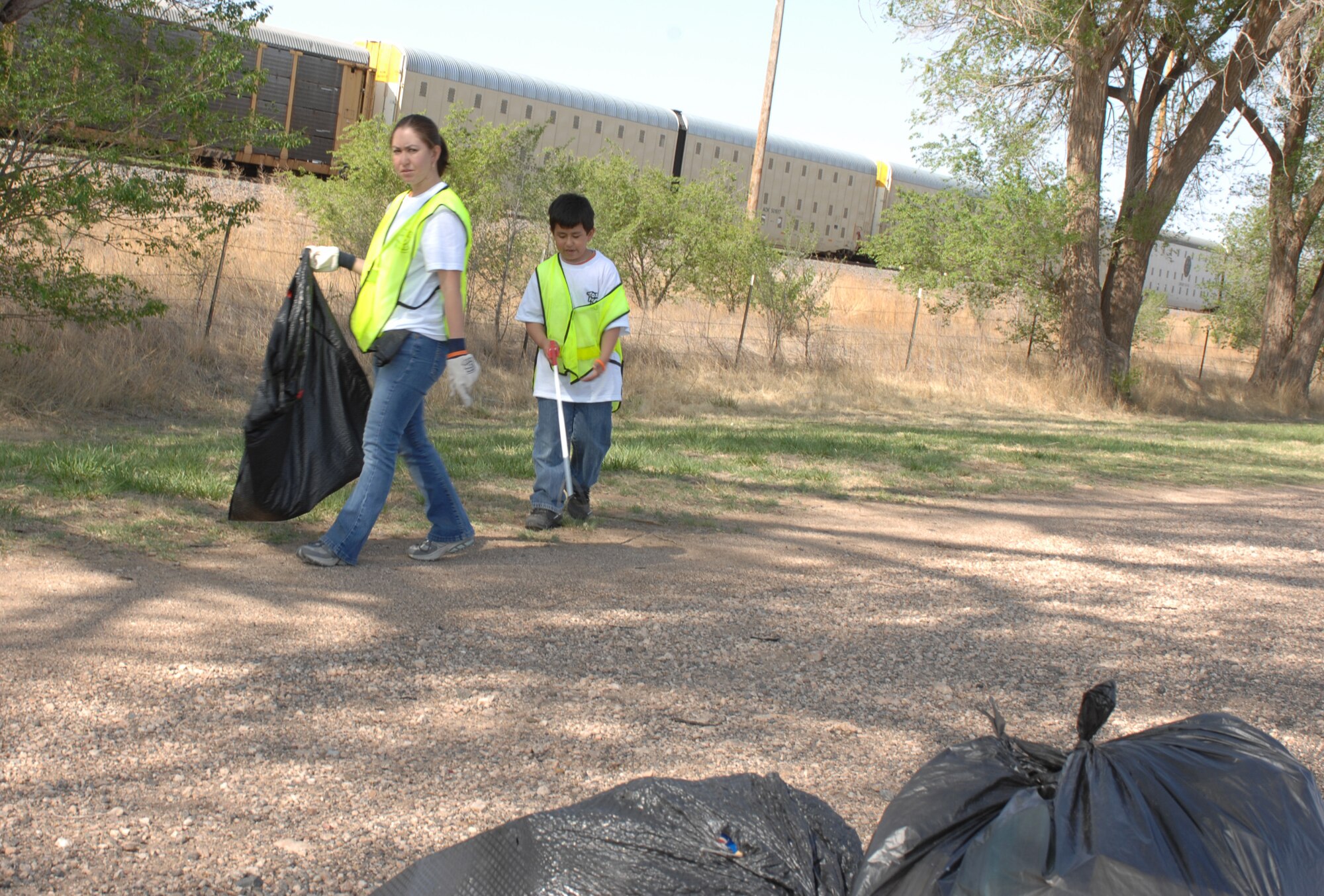 CANNON AIR FORCE BASE, N.M. -- Senior Airman Oralia Buenrostro, 27th Special Operations Medical Support Squadron, and her son, Juan, 9, pick up trash near the railroad tracks on Mabry Drive in Clovis, N.M. More than 250 Airmen participated in the Great American Cleanup effort on April 26, and with the community, collected more than 94,000 pounds of trash. (U.S. Air Force by Greg Allen)