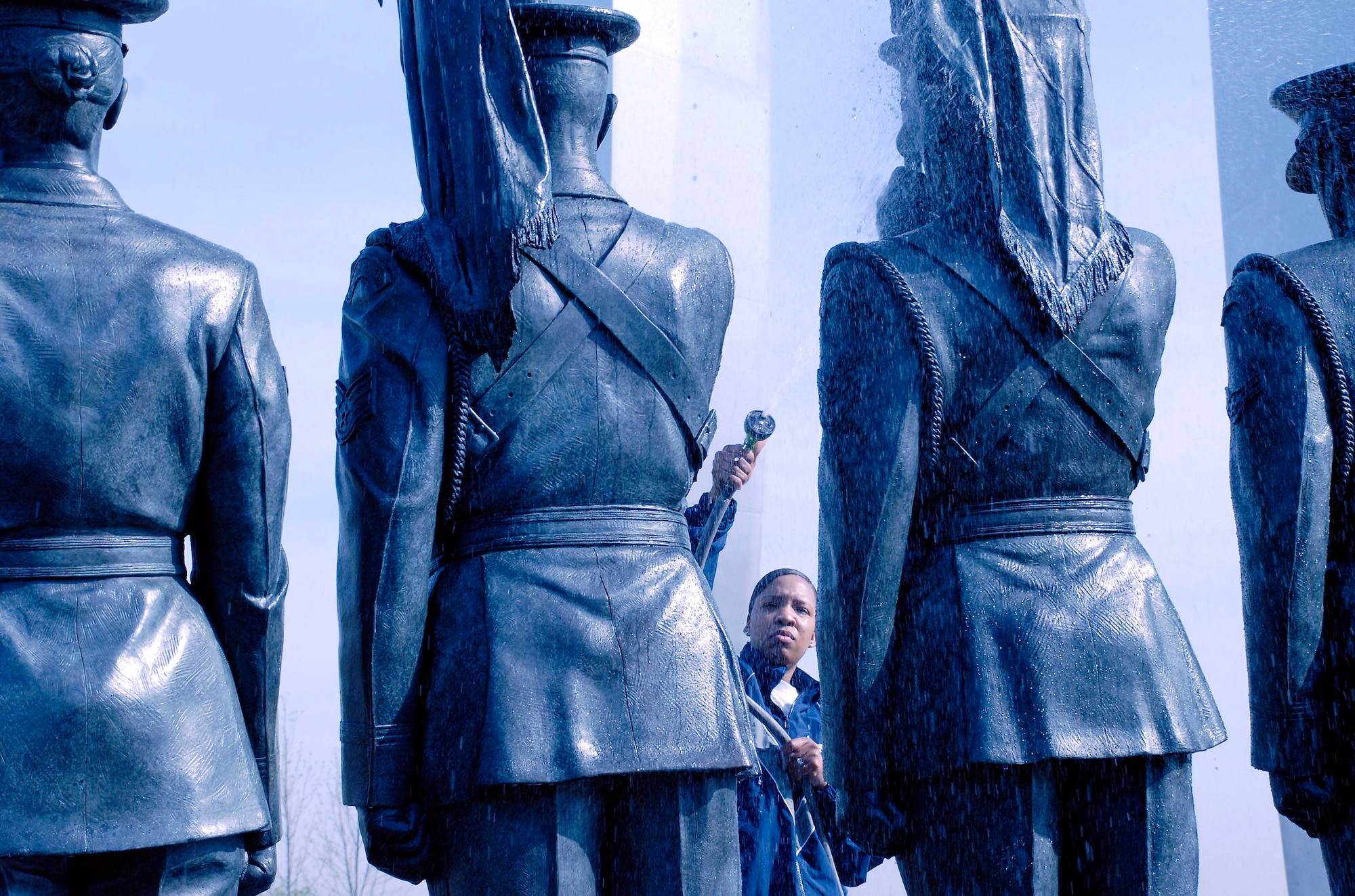 Staff Sgt. Shannah Holmes hoses down a bronze honor guard statue during a work party April 19 at the Air Force Memorial.  More than 50 volunteers from Air Force Sergeants Association Chapter 300 in Washington D.C. gathered to help spruce up the site.  Dedicated on Oct., 14, 2006, the memorial honors the service and sacrifice of the men and women of the United States Air Force and its predecessor organizations.  The wall bears the inscriptions of combat campaigns and expeditionary operations and contains the words of Air Force leaders that relate to the service's core values of Integrity First, Service Before Self and Excellence in All We Do. The memorial is located just outside the nation's capital in Arlington, Va., adjacent to Arlington National Cemetery and overlooking the Pentagon.  Sergeant Holmes works in the Pentagon in the Secretary of the Air Force Financial Management and Comptroller's Office.  (U.S. Air Force photo/Senior Master Sgt. Matt Proietti)