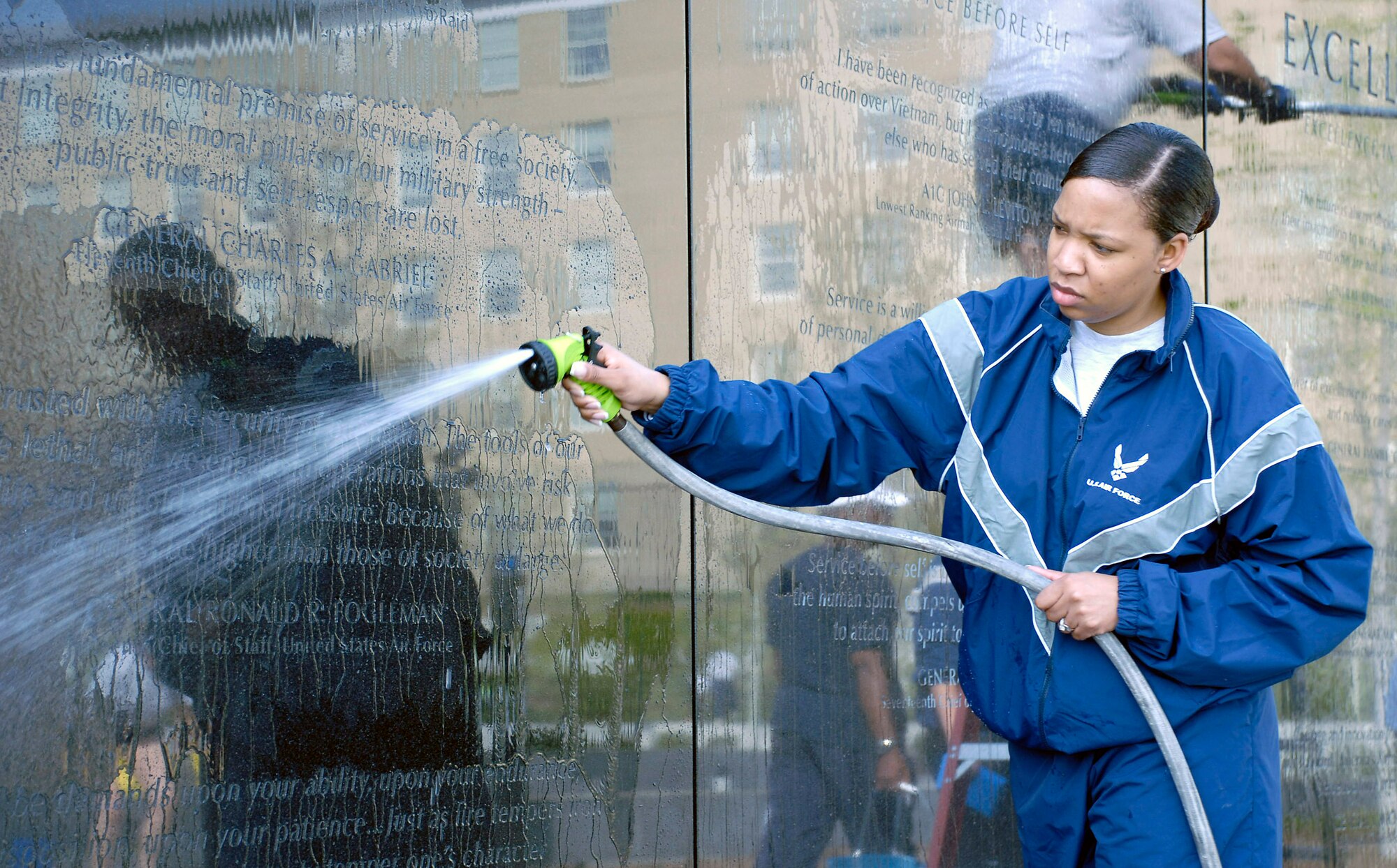 Staff Sgt. Shannah Holmes hoses down the granite wall during a work party April 19 at the Air Force Memorial.  More than 50 volunteers from Air Force Sergeants Association Chapter 300 in Washington D.C. gathered to help spruce up the site.  Dedicated on Oct., 14, 2006, the memorial honors the service and sacrifice of the men and women of the United States Air Force and its predecessor organizations.  The wall bears the inscriptions of combat campaigns and expeditionary operations and contains the words of Air Force leaders that relate to the service's core values of Integrity First, Service Before Self and Excellence in All We Do. The memorial is located just outside the nation's capital in Arlington, Va., adjacent to Arlington National Cemetery and overlooking the Pentagon.  Sergeant Holmes works in the Pentagon in the Secretary of the Air Force Financial Management and Comptroller's Office.  (U.S. Air Force photo/Senior Master Sgt. Matt Proietti)