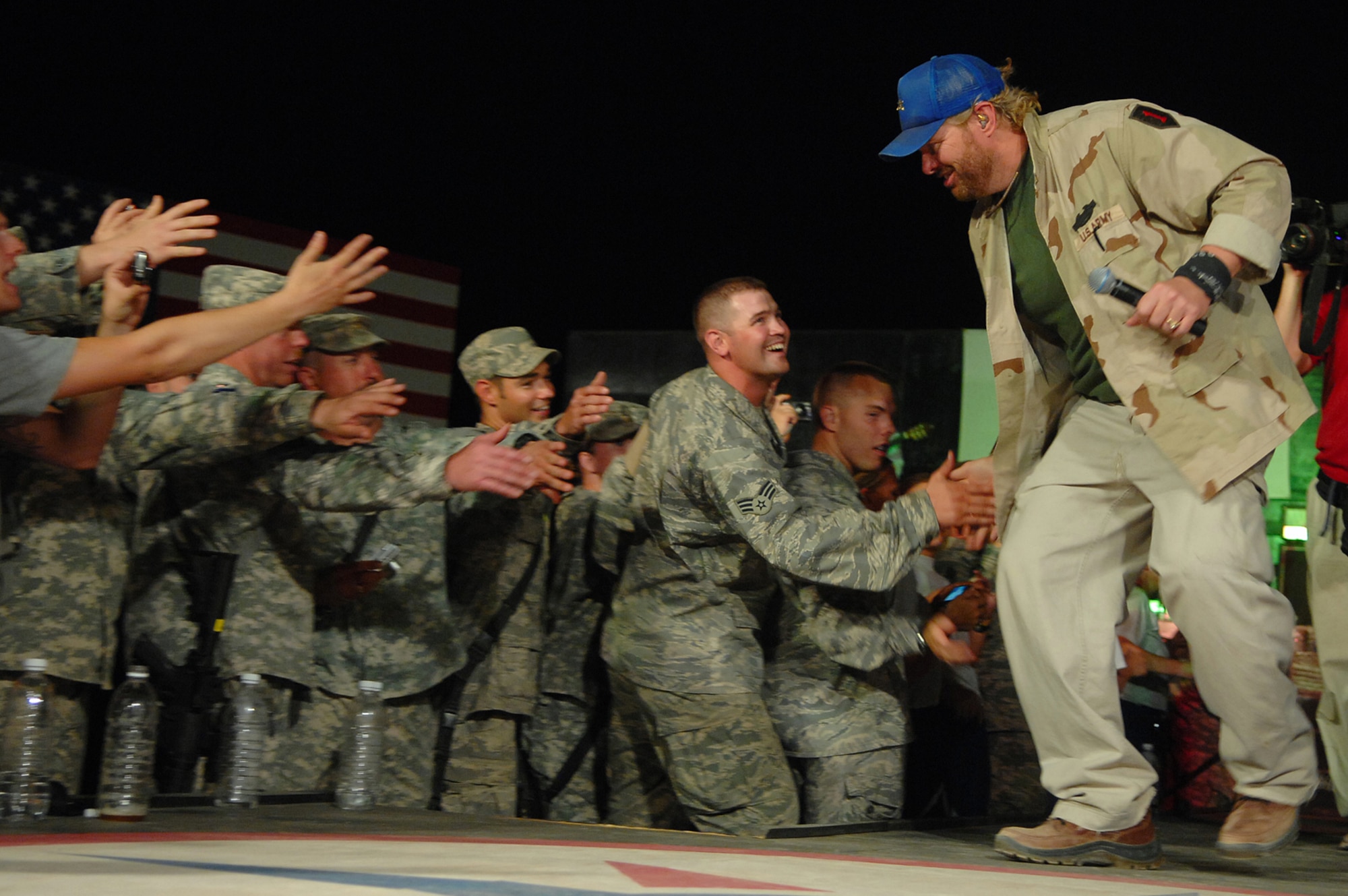BALAD AIR BASE, Iraq -- Toby Keith grabs the outstretched hand of Senior Airman Brent Contratto, 332nd Expeditionary Security Forces Squadron force protection Airman, during a concert for servicemembers here, April 28. Mr. Keith told those in attendance that he was proud of their service and thankful for their efforts in fighting terrorists and keeping America free. He referred to military members as "warriors" and was present for the re-enlistments of five Soldiers stationed at Logistics Support Agency Anaconda, which is co-located with Balad. Mr. Keith is wrapping up his sixth USO tour in Iraq; his show at Balad marked his 117th show in the Area of Responsibility. (U.S. Air Force photo/ Senior Airman Julianne Showalter)