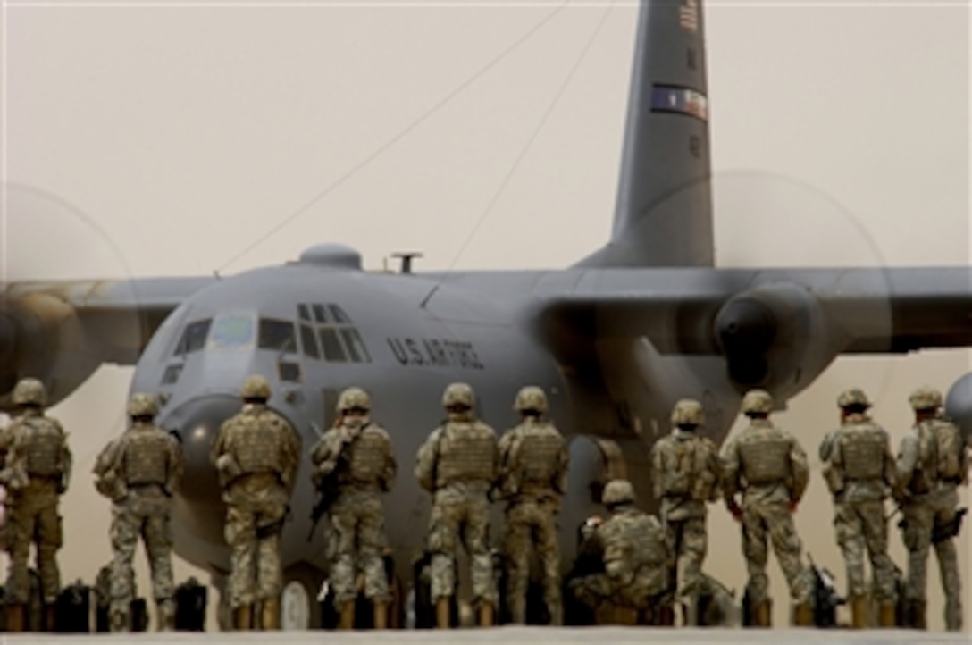 U.S. Army soldiers watch a C-130 Hercules aircraft taxi as they wait to board a C-17 Globemaster III aircraft at Sather Air Base, Iraq, on April 19, 2008.  Approximately 32,000 service members per month process through the base's passenger terminal.  