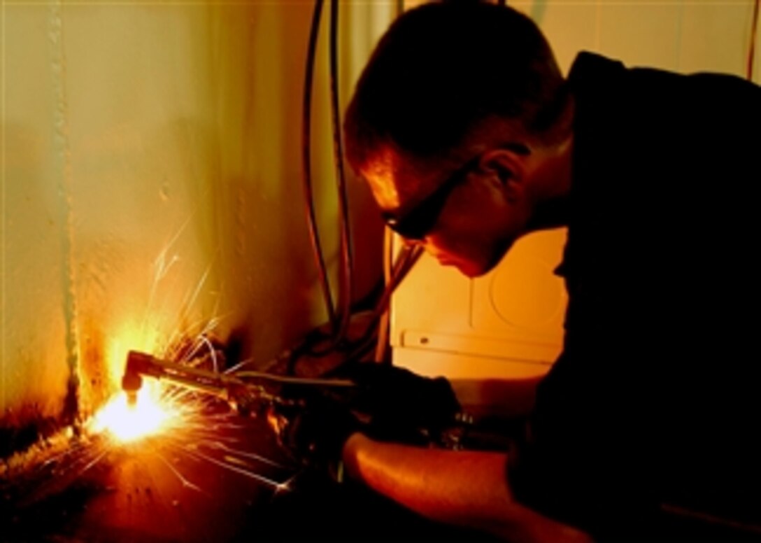 U.S. Navy Petty Officer 3rd Class Michael Poling uses an oxygen/acetylene torch to remove a work table aboard the aircraft carrier USS Theodore Roosevelt, Atlantic Ocean, April 28, 2008. 