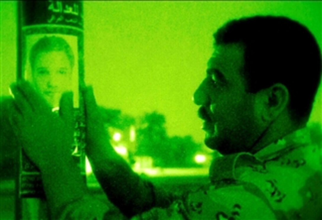 An Iraqi soldier posts a wanted poster on a street lamp near a joint security station in Sadr City, Iraq, April 20, 2008. 
