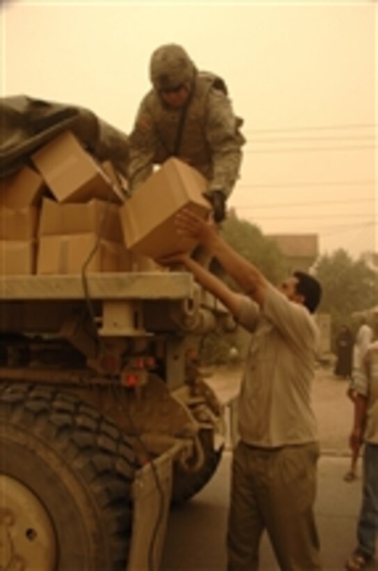 A U.S. Army soldier passes a box of supplies to a local during a humanitarian aid mission at a mosque in Amariyah, Iraq, on April 17, 2008.  The soldier is from Charlie Troop, 4th Squadron, 10th Cavalry Regiment, 4th Infantry Division.  