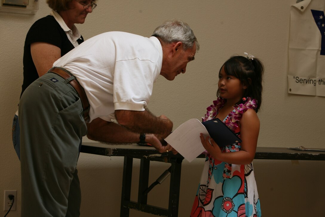 HONOLULU --  Rhyza LaForce, 7, is congratulated by retired Marine Colonel John Bates for winning the grand prize in the ASYMCA's "My Military Hero" essay contest at the Pearl Harbor Community Center, April 30.