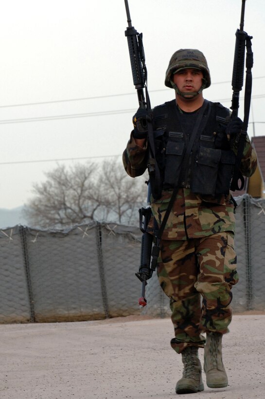 Senior Airman Benjamin Figueroa, 28th Civil Engineer Squadron electrical systems journeyman, transports three M-16 assault rifles to a weapons cleaning area during a field training exercise here on April 30. The exercise was designed to maintain combat skills necessary for small unit tactics and bare-base setup procedures. (U.S. Air Force photo/Senior Airman Marc Lane) 
