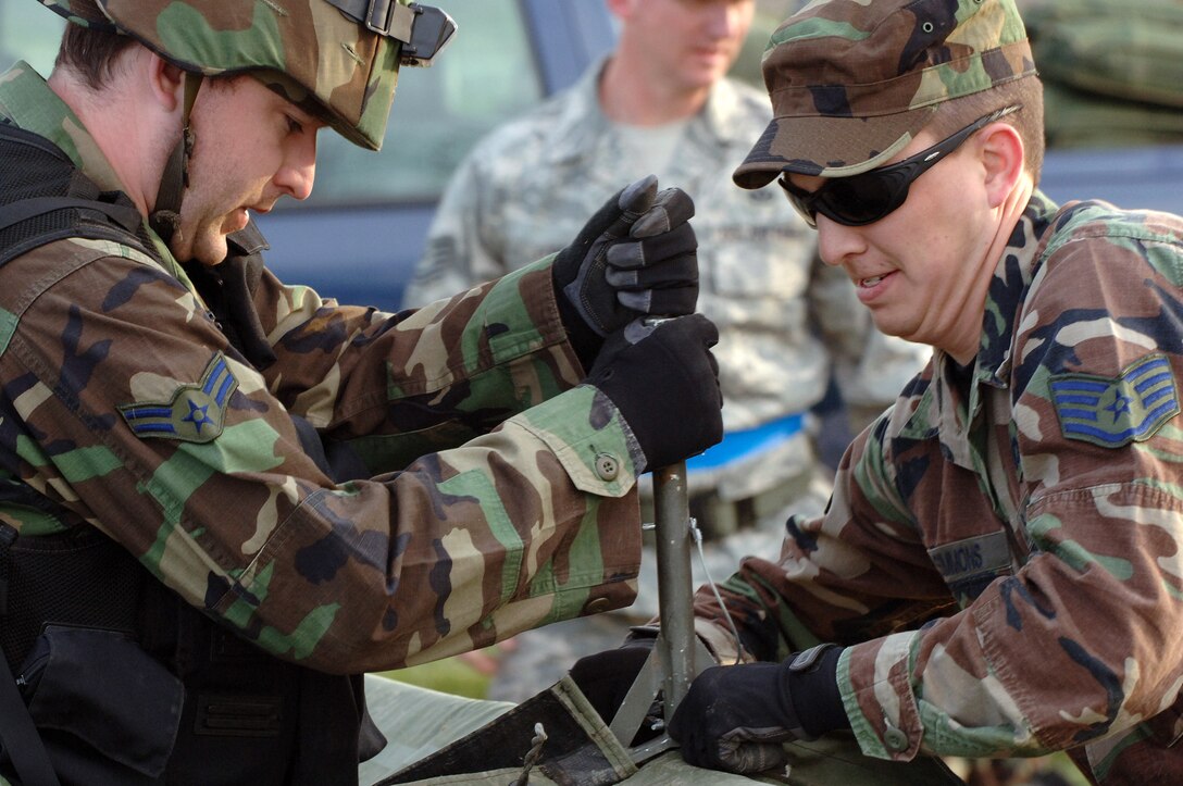(Left) Airman 1st Class Chad Harper, 28th Civil Engineer Squadron fire fighter, and Staff Sgt. Jerry Simmons, 28 CES electrical systems craftsman, disassemble a temper tent during a field training exercise here on April 30. The exercise was designed to maintain combat skills necessary for small unit tactics and bare-base setup procedures. (U.S. Air Force photo/Senior Airman Marc Lane) 
