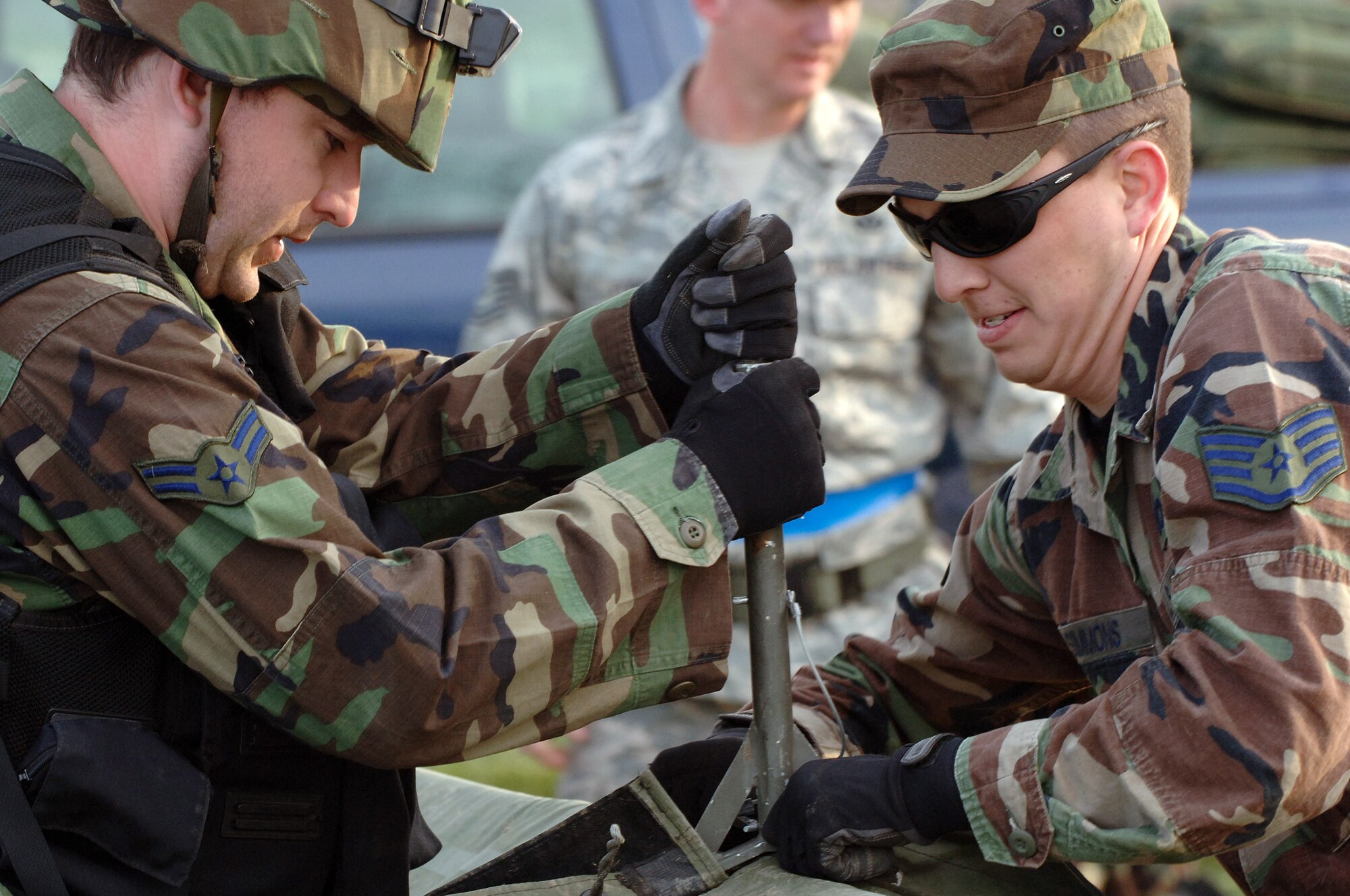 (Left) Airman 1st Class Chad Harper, 28th Civil Engineer Squadron fire fighter, and Staff Sgt. Jerry Simmons, 28 CES electrical systems craftsman, disassemble a temper tent during a field training exercise here on April 30. The exercise was designed to maintain combat skills necessary for small unit tactics and bare-base setup procedures. (U.S. Air Force photo/Senior Airman Marc Lane) 