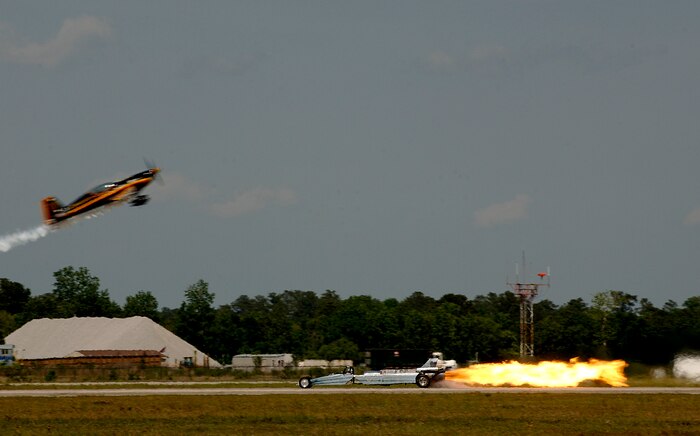 Patty Wagstaff flies her Extra 300S over retired Master Sgt. Bill Braack in the Air Force Reserve Jet Car before the two race during their practice April 25 before the air expo on the Charleston AFB flightline. (U.S. Air Force photo/Senior Airman Nicholas Pilch)