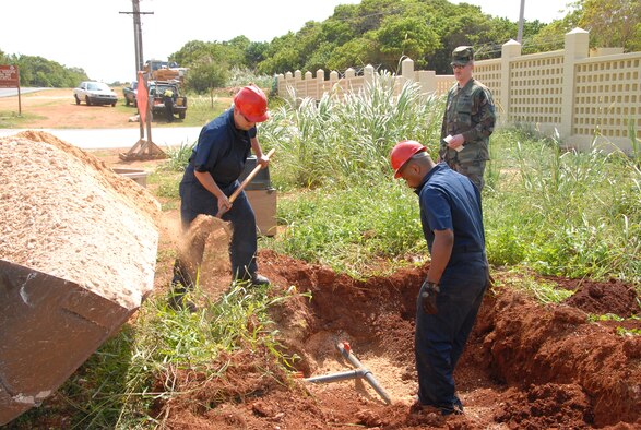 Tech. Sgt. Jerry Hedstrom looks on as Technical Sergeants Todd McGee and Javier Vigil finish a new pipe and valve installation at the gate of Northwest Field, Guam. (U.S. Air Force photo by Capt. Torri White)