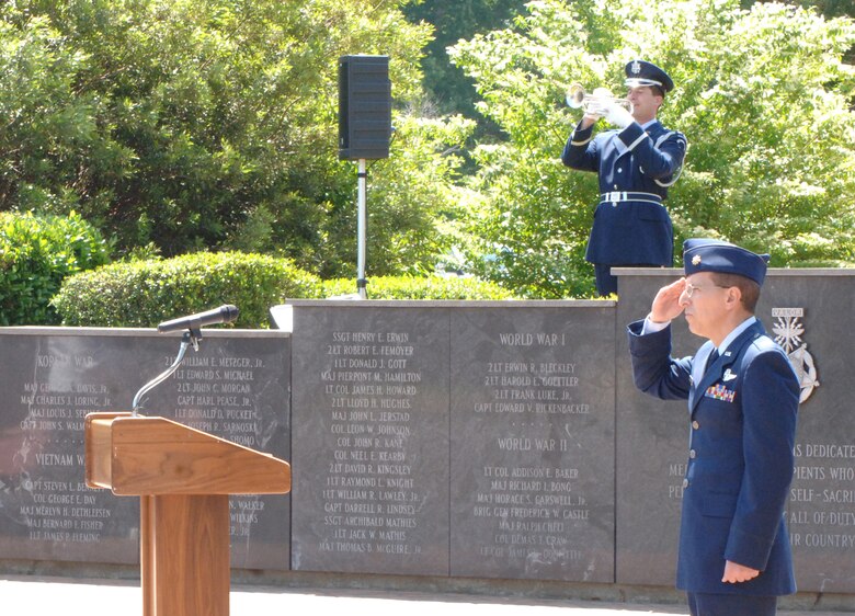 First Lt. James Schmidt, Specialized Undergraduate Pilot Training class 08-10, plays "Taps" on the bugle as Maj. Dave Garrison, 43rd Flying Training Squadron, and the rest of the crowd pays respects to the American Flag. (U.S. Air Force photo by Airman Josh Harbin)