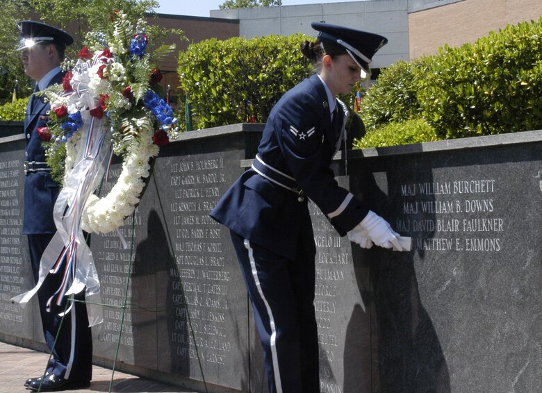Honor Guardsman Amanda Fitzgerald removes the tape covering 2nd Lt. Matthew Emmons's name on the memorial wall in Smith Plaza Tuesday at the memorial service. Both Lieutenant Emmons and Maj. Blair Faulkner's names were engraved in the wall. (U.S. Air Force photo by Airman Josh Harbin)
