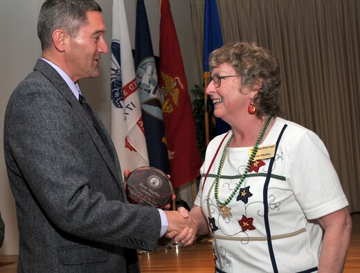 Col. Paul Gydesen, 341st Space Wing vice commander, shakes the hand of a very surprised Rose Maflin, as she brought forward to receive the Volunteer of the Year Award. Mrs. Maflin was chosen by the rest of her peers in the Montana Military Retiree Council for her outstanding contributions to the ongoing efforts for Operations Happy Holidays. (U.S. Air Force photo/John Turner)