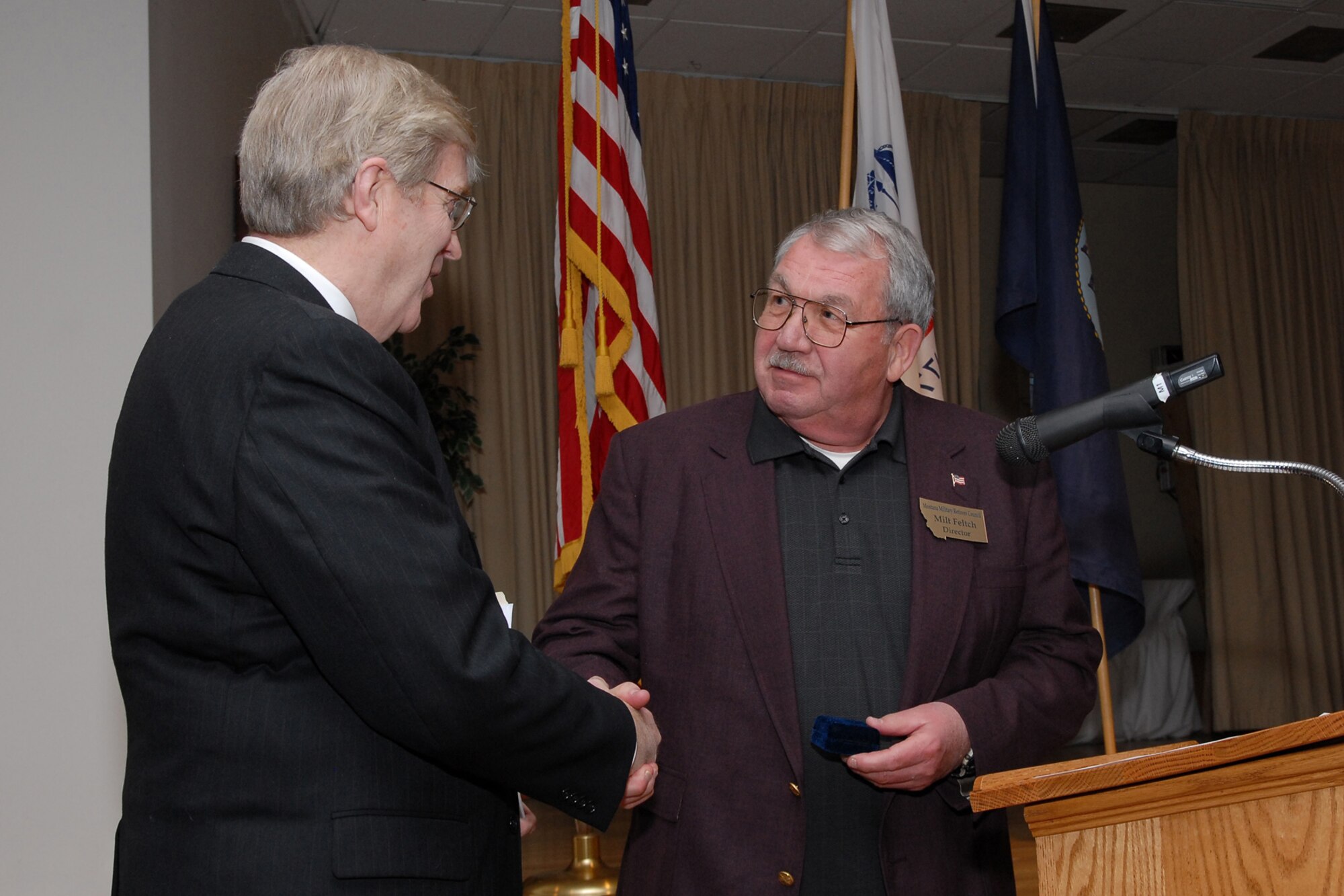 Retired Col. Milt Felth shakes hands with Legislative Director for the National Association for Unifomed Services Rick Jones as he prepares to present him with a gift. Mr. Jones was the keynote speaker for the retiree appreciation brunch April 26. (U.S. Air Force photo/John Turner)