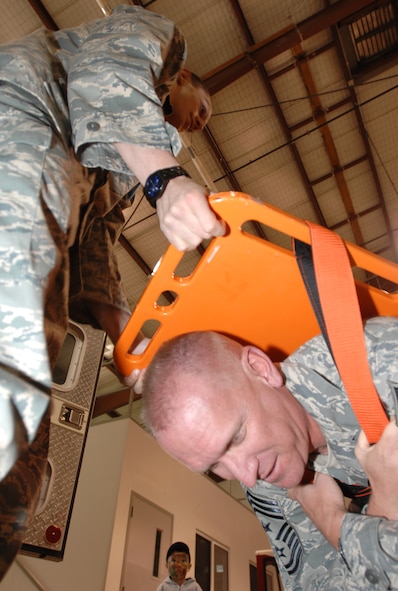 WHITEMAN AIR FORCE BASE - Airman 1st Class Michael Shamp, 509th Medical Operations Squadron, holds Chief Master Sgt. Brian Hornback, 509th Bomb Wing command chief, upside down on a backboard during Operation Spirit April 26 while being held on by only Velcro straps to demonstrate the strength of the Velcro system. (U.S. Air Force photo/Staff Sgt. Jason Barebo)