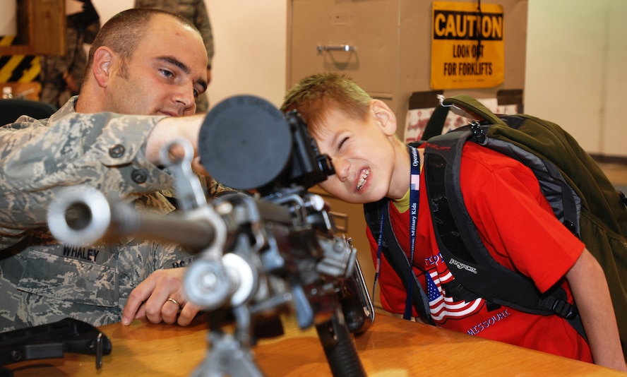 WHITEMAN AIR FORCE BASE - Staff Sgt. Charles Whaley (left), 509th Security Forces Squadron, makes adjustments for Justin Laurie (right) as he looks through a scope attached to a M249 during Operation Spirit April 26. the 509th SFS was available throughout the event to answer questions and give the children some hands-on experience with some of the equipment they use. (U.S. Air Force photo/Staff Sgt. Jason Barebo)