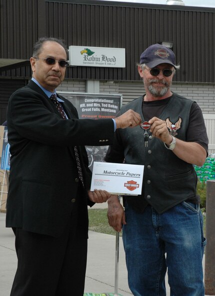 Russell Mendoza, district sales manager of Sandberg and Sikorski, presents retired Master Sgt. Ted Baker, the keys and title to his new Harley 1200 Sportster outside the Base Exchange April 28. Sandberg and Sikorski is a New York based company that supplies jewelry to AAFES. The company sponsored this AAFES-wide sweepstakes and Mr. Mendoza came to Malmstrom to present Mr. Baker his prize. (U.S. Air Force photo/Airman 1st Class Emerald Ralston)