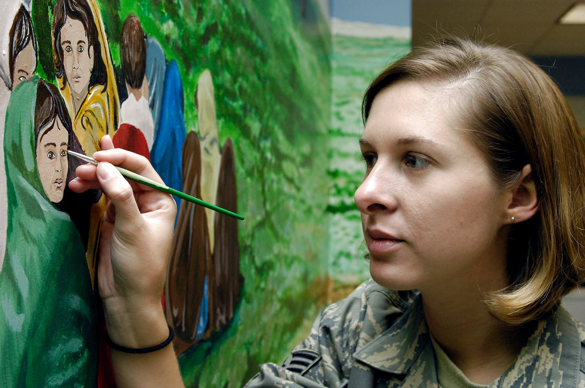 Staff Sgt. Jessica Newcomb does some final touch ups on a mural she and 38 other artists painted in the hospital conference room at Bagram Air Base, Afghanistan, April 29. The mural features local culture and a panoramic view of the mountains near Bagram AB. Sergeant Newcomb is a Craig Joint Theater Hospital medical technician. (U.S. Air Force photo/Master Sgt. Demetrius Lester)