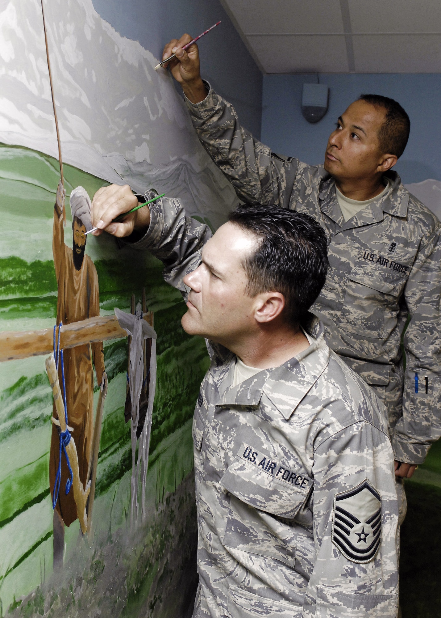 Master Sgt. Albert Greig (front) and Master Sgt. Cruz Torres Jr., perform some final touch ups on a mural they and other artists painted in the hospital conference room at Bagram Air Base, Afghanistan, April 24. The mural features local culture and a panoramic view of the mountains near Bagram AB. Sergeant Greig is the Craig Joint Theater Hospital medical logistics superintendent and Sergeant Torres is NCO in charge of the emergency room. (U.S. Air Force photo/Master Sgt. Demetrius Lester)