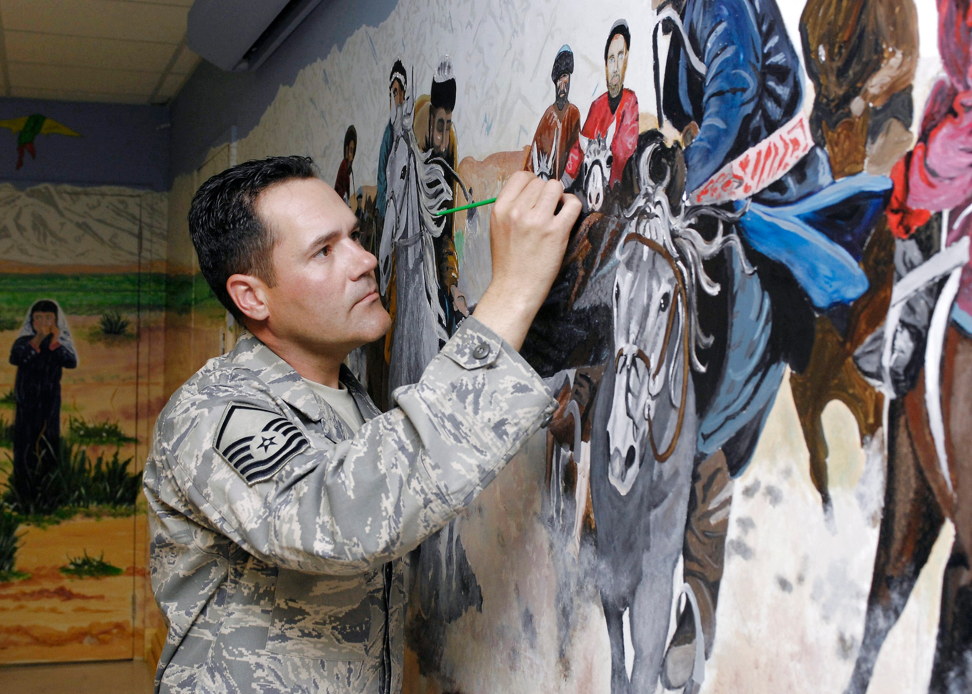 Master Sgt. Albert Greig performs some final touch ups on a mural he and 38 other artist painted in the hospital conference room at Bagram Air Base, Afghanistan, April 24. The mural featured local culture and a panoramic view of the mountains near Bagram AB. Sergeant Greig is the Craig Joint Theater Hospital medical logistics superintendent. (U.S. Air Force photo/Master Sgt. Demetrius Lester)