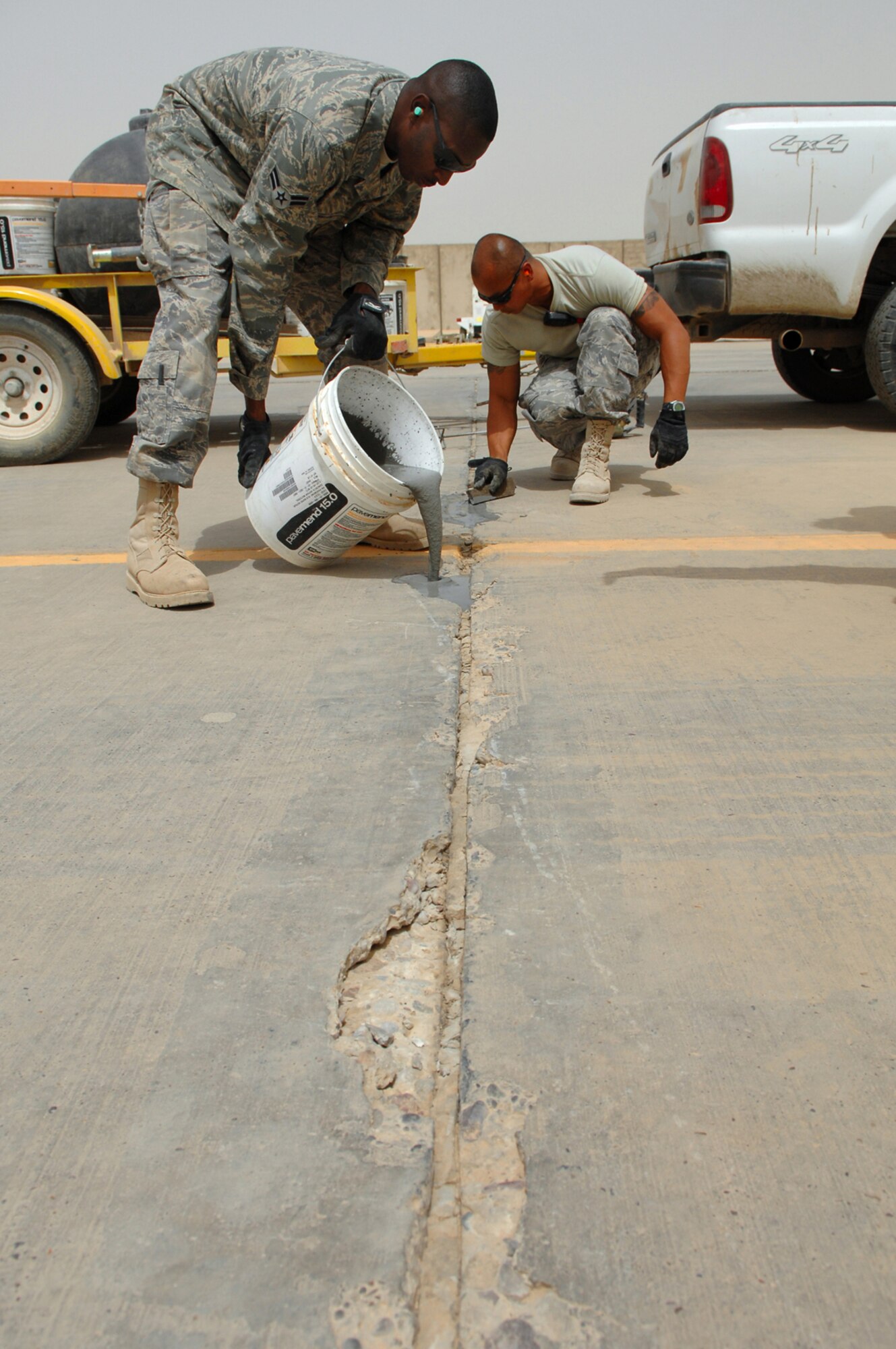 BALAD AIR BASE, Iraq -- Airman 1st Class Eric Culbreath, 332nd Expeditionary Civil Engineer Squadron spall unit member, pours a quick-set concrete into a spall here, April 28. Spalls are sections of the runway that crack or split. The spall unit is on call 24 hours a day ready to respond immediately to the need for repairs. Airman Culbreath is deployed from McGuire Air Force Base, N.J. (U.S. Air Force photo/ Senior Airman Julianne Showalter)
