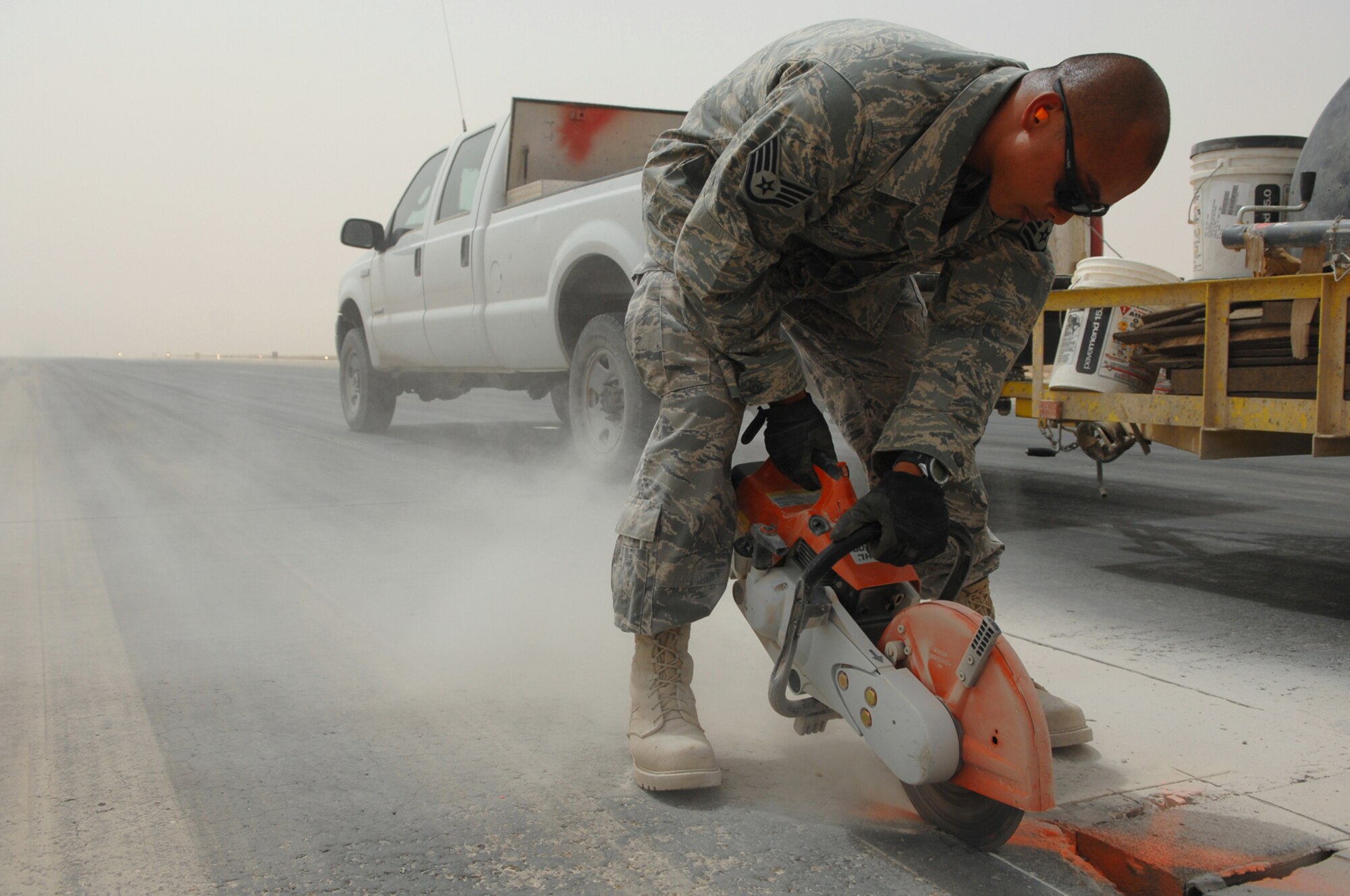 BALAD AIR BASE, Iraq -- Staff Sgt. Edward Nicandro, 332nd Expeditionary Civil Engineer Squadron spall unit member, cuts around a spall before pouring a quick-setting concrete here, April 28. Spalls are sections of the runway that crack or split. The spall unit is on call 24-hours a day for any repairs that may need to be done, allowing flight operations to continue. Sergeant Nicandro is deployed from Peterson Air Force Base, Colo. (U.S. Air Force photo/ Senior Airman Julianne Showalter)