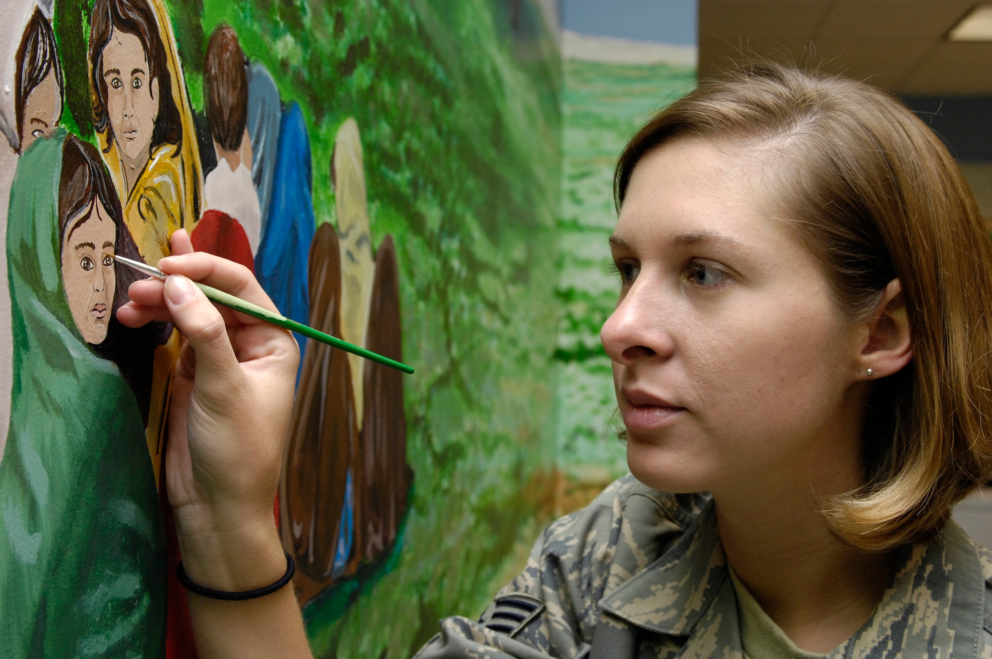BAGRAM AIR FIELD, Afghanistan - Staff Sgt. Jessica Newcomb, Craig Joint Theater Hospital medical technician, does some final touch ups on a mural she and 38 other artists painted in the hospital conference room here April 29. The mural features local culture and a panoramic view of the mountains from Bagram. Sergeant Newcomb is deployed from the 932nd Aeromedical Staging Squadron, Scott Air Force Base, Ill. (U.S. Air Force photo by Master Sgt. Demetrius Lester)