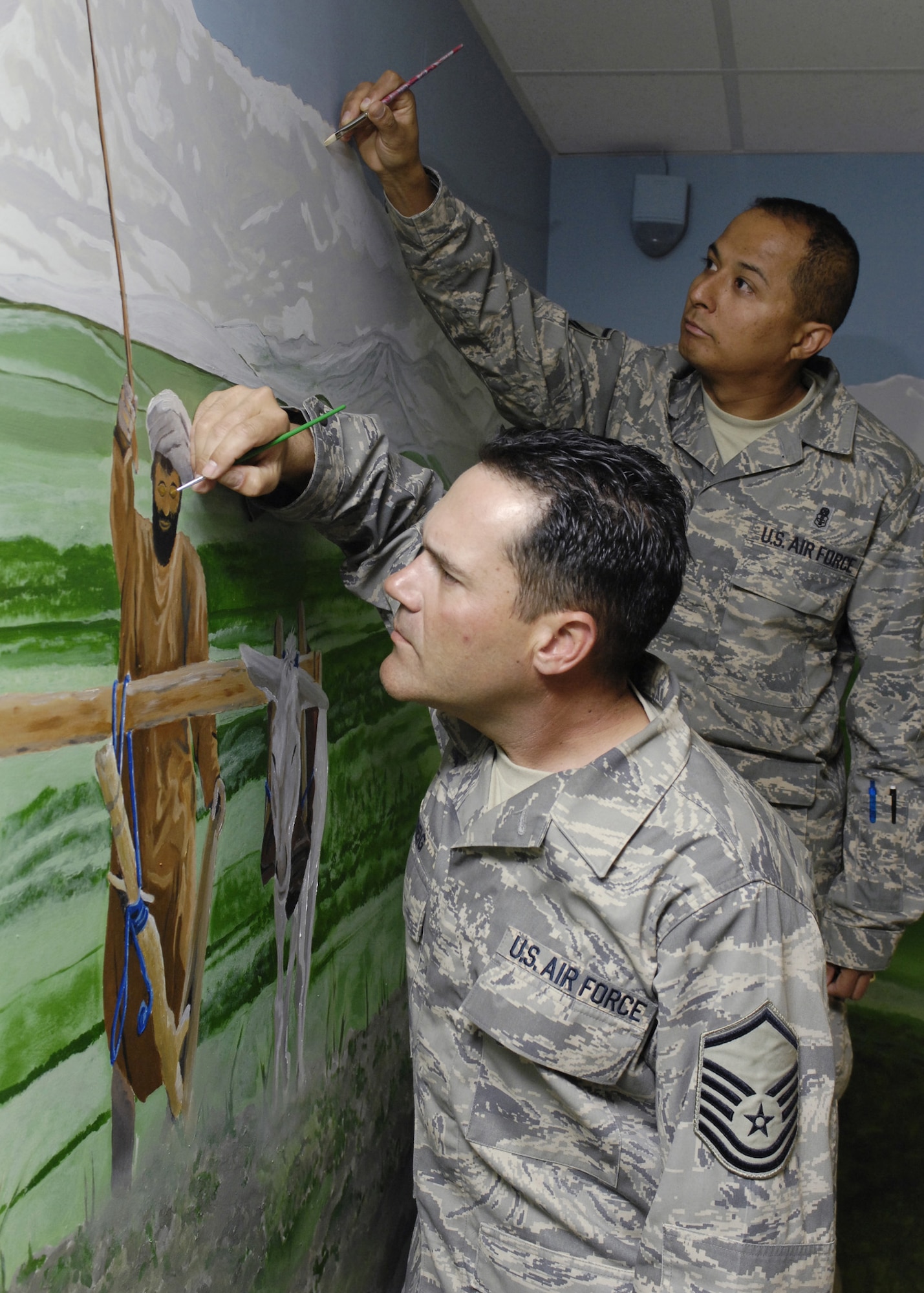 BAGRAM AIR FIELD, Afghanistan - Master Sgt. Albert Greig (front), Craig Joint Theater Hospital medical logistics superintendent, and Master Sgt. Cruz Torres Jr., NCO-in-charge Emergency Room, perform some final touch ups on a mural they and other artists painted in the hospital conference room here April 24. The mural features local culture and a panoramic view of the mountains from Bagram. Sergeant Greig is deployed from the 1st Special Operations Support Squadron, Hurlburt Field, Fla., and Sergeant Torres is deployed from the 710th Medical Squadron, Offut Air Force Base, Neb. (U.S. Air Force photo by Master Sgt. Demetrius Lester)