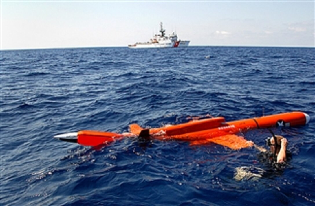 U.S. Navy Petty Officer 3rd Class Scott Roark, a culinary specialist stationed aboard the USS Farragut, retrieves a flight drone after a gun exercise with the help of a Coast Guard Northland small boat crew, off the coast of Brazil, April 26, 2008. 

